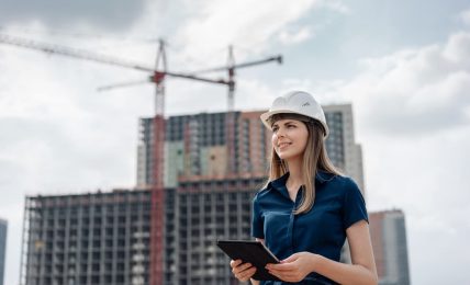 Junge Bauingenieurin auf Baustelle mit Laptop