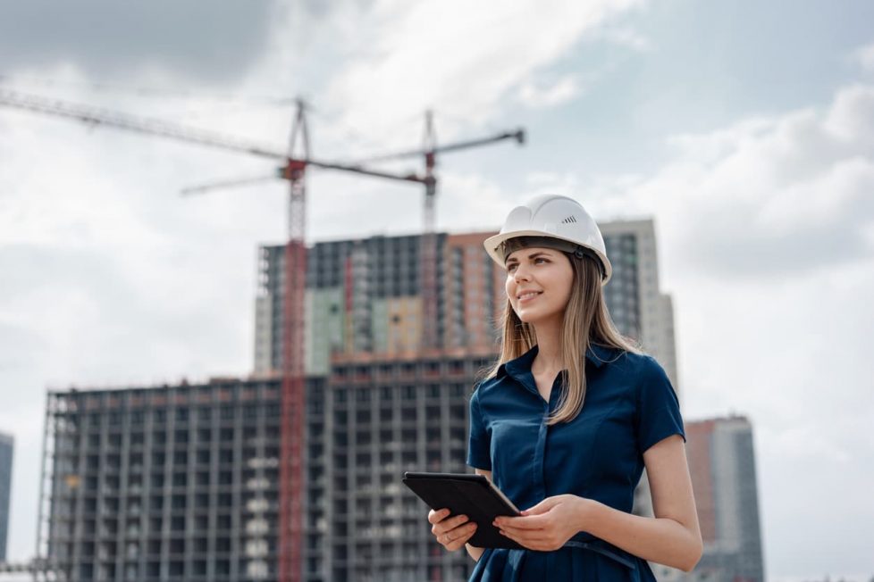 Junge Bauingenieurin auf Baustelle mit Laptop