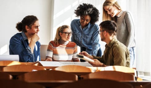 Fünf Arbeitskollegen unterhalten sich am Tisch über Berufe in der Erwachsenenbildung