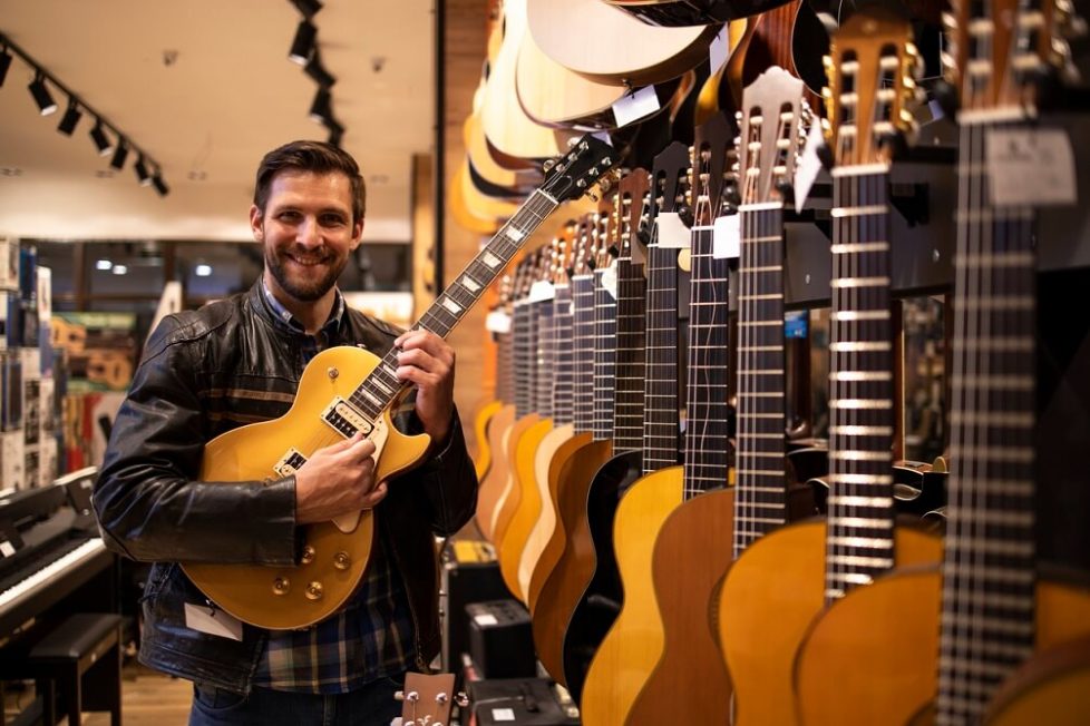 Ein Azubi der Musikfachhändlre Ausbildung hält eine E-Gitarre in den Händen im Musikgeschäft