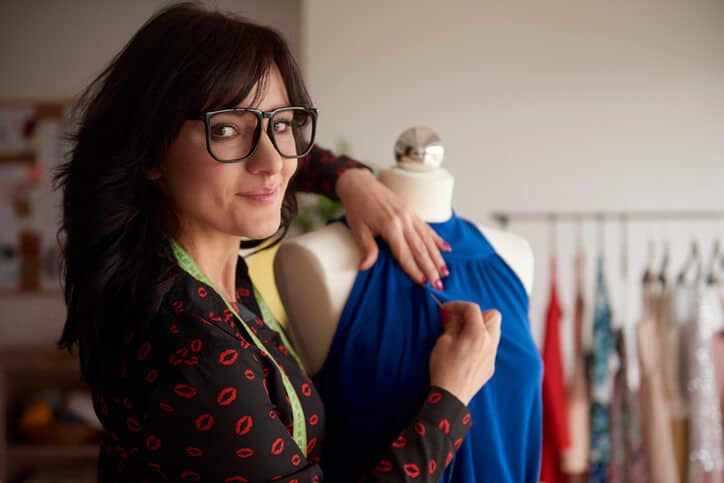 Eine dunkelhaarige Frau mit Brille im Attelier in der Textilgestalter Ausbildung