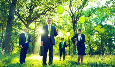 Grüne Unternehmen: Mitarbeiter stehen im Grünen und halten Ballons hoch