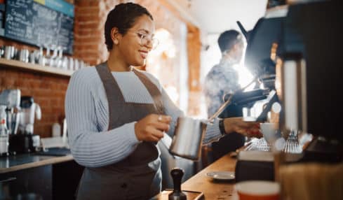 Junge Frau hinter der Theke macht Barista Ausbildung