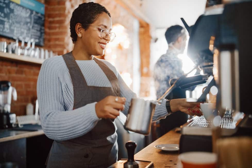 Junge Frau hinter der Theke macht Barista Ausbildung