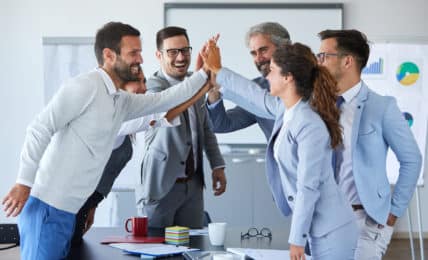 Team in Büro klatscht ab - Teamfähigkeit