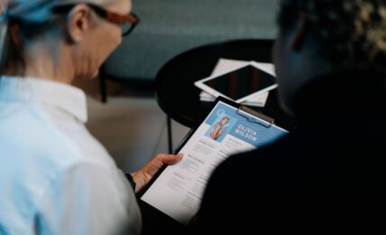 Business professionals conducting an interview with resume on clipboard in an office setting.
